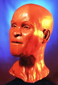 Busto do rosto de uma mulher. Ela tem traços negroides.